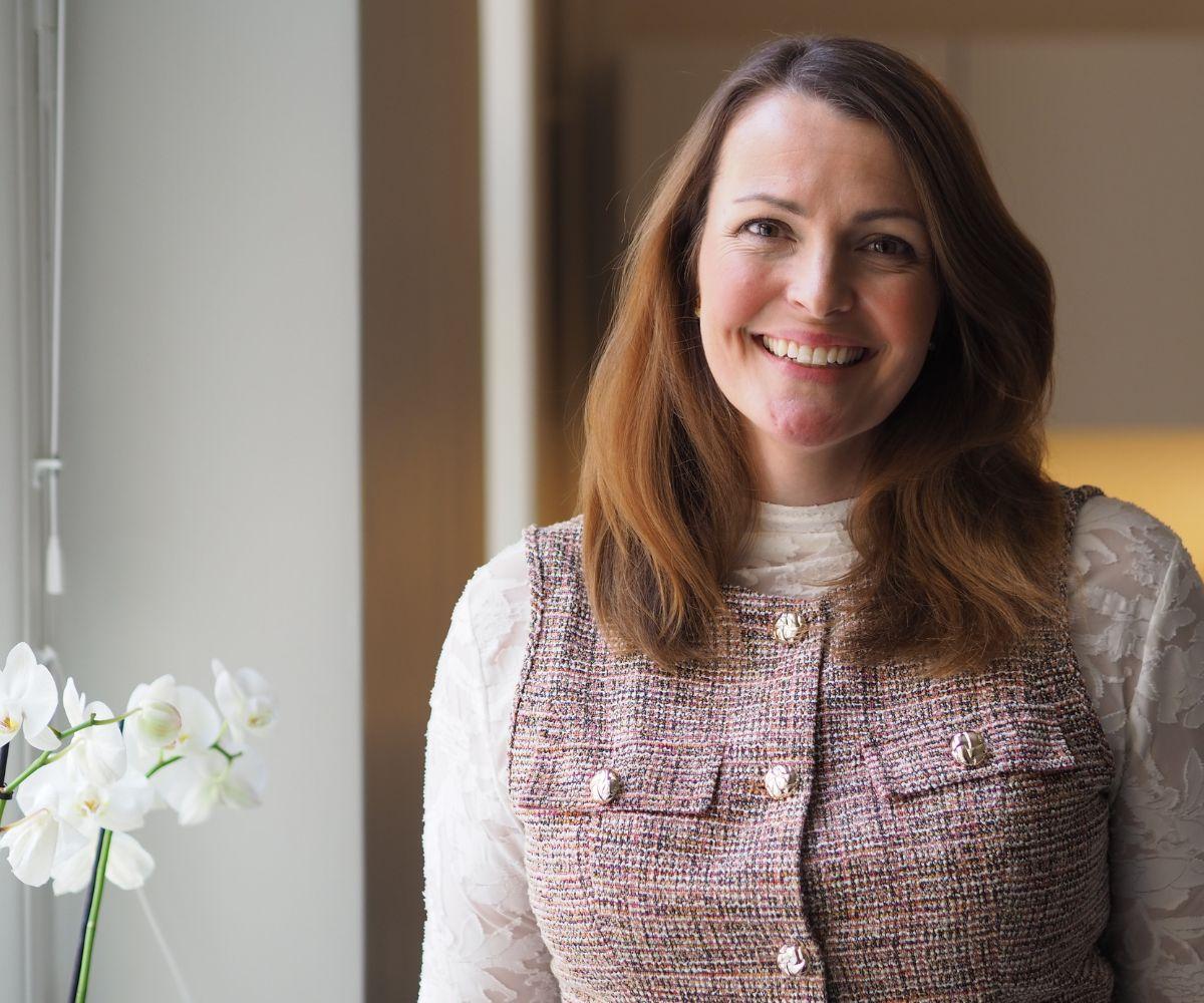 Annina Alexandersson står vid ett fönster och ler mot kameran.