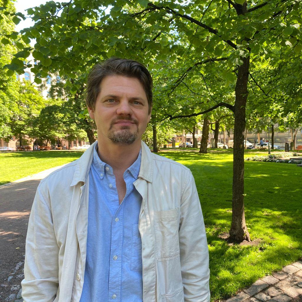 Mikko Reponen med grönskande park i bakgrunden.
